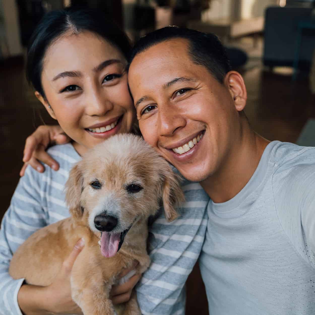 man and woman smiling with dog during at-home addiction rehab