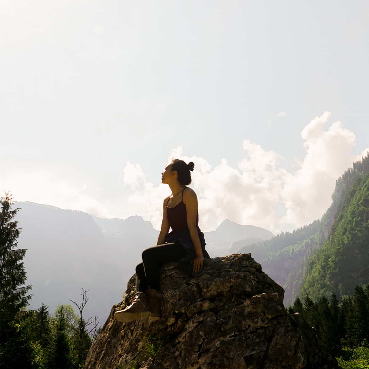 woman sitting on a rock in the mountains during at-home addiction rehab